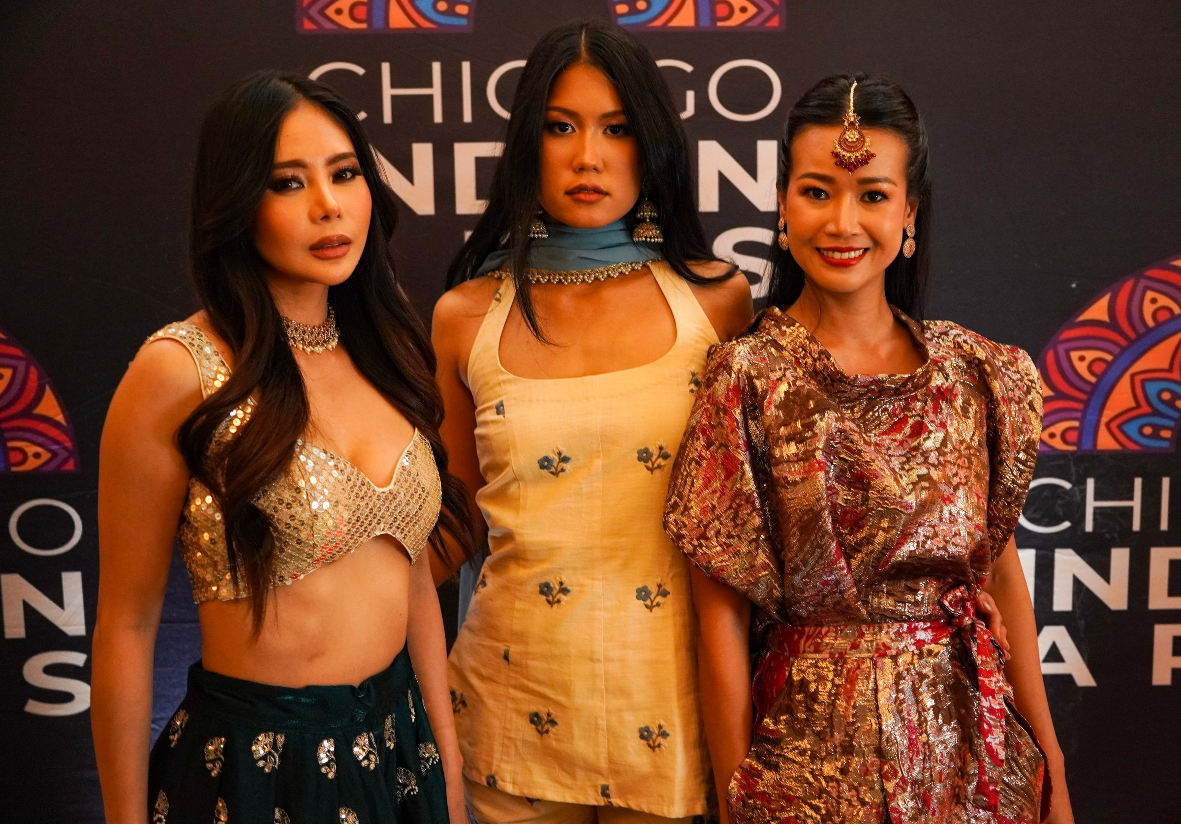 Three people in embellished, cream and patterned looks pose against a Chicago Indian Arts backdrop.